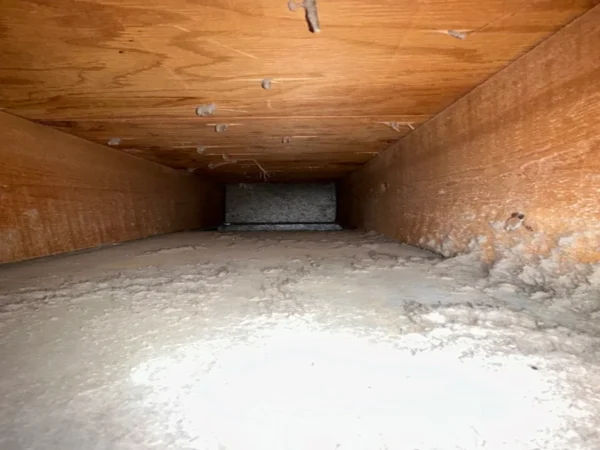 Air duct before cleaning - a heavy layer of dust and lint inside the duct