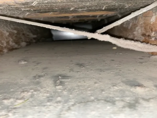 Main duct before cleaning - dust and lint hanging from the support straps