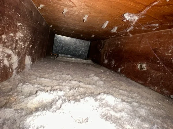 Wooden supply plenum before cleaning - a heavy layer of dust on the floor